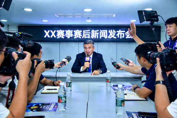 赛后新闻发布会场景，主教练面对媒体记者回答关于比赛的提问
